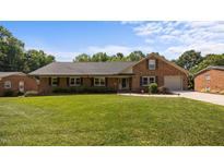 Charming brick home featuring a well-manicured lawn, attached garage, and inviting curb appeal at 1926 Downing Dr, Burlington, NC 27215