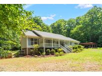 Charming single-story home featuring a welcoming front porch and beautifully landscaped yard surrounded by mature trees at 211 Hills Of The Haw Rd, Pittsboro, NC 27312