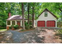 Charming home with a two-car garage and brick chimney surrounded by lush trees and a gravel driveway at 224 Fleming Dr, Durham, NC 27712
