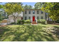 Traditional two-story home with a red front door, attached garage, and a well-manicured lawn and landscaping at 2704 Farnborough Rd, Raleigh, NC 27613