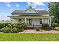 Charming home with a covered front porch, beautiful landscaping, and brick pathway leading to the entrance at 419 Mabry Rd, Angier, NC 27501