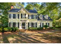 Charming yellow two-story home with black shutters surrounded by lush greenery and mature trees at 6201 King Croydon Ct Ct, Raleigh, NC 27603