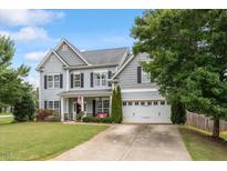 Charming two-story home with a well-manicured lawn, gray siding, and attached two car garage at 6901 Rex Rd, Holly Springs, NC 27540