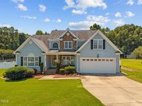 Charming two-story home with stone accents, attached garage, and well-manicured lawn under a beautiful sky at 6965 Ogburn Farms Dr, Willow Springs, NC 27592