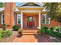 Charming brick home featuring a red front door with decorative glass and a brick walkway lined with flowers at 8851 Mariner Dr, Raleigh, NC 27615