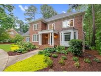 Charming two-story brick home with a welcoming porch, lush landscaping, and mature trees at 105 Bathgate Ln, Cary, NC 27513