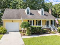 Charming yellow home with a well-manicured lawn, dormers, and an attached garage at 11901 N North Exeter Way Way, Raleigh, NC 27613