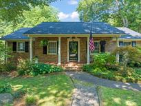 Charming brick home featuring a manicured front yard and inviting front porch with an American flag at 1311 Norton St, Durham, NC 27701