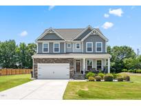 Beautiful two-story home featuring a stone and gray facade with a well-manicured lawn at 1321 White Spruce Dr, Willow Springs, NC 27592