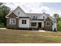 Beautiful home with stone and white siding, a covered porch, and professional landscaping at 225 Whistlers Cv, Louisburg, NC 27549