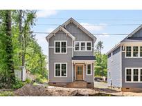 Charming two-story home with gray siding, white trim, and a welcoming front porch in a wooded neighborhood at 313 W Murray Ave, Durham, NC 27704