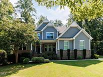 Charming two-story home featuring manicured lawn and mature trees on a sunny day at 354 Crimson Way, Pittsboro, NC 27312