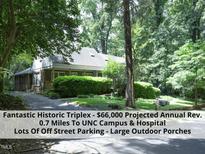Charming single-story triplex with brick and white siding nestled among lush greenery at 407 Coolidge St # A, Chapel Hill, NC 27516