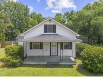 Charming white home featuring a covered front porch, black shutters, and beautifully maintained landscaping at 4880 Old Us Hwy 64, Zebulon, NC 27597