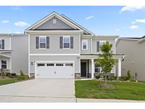 Charming two-story home with gray siding, stone accents, and a well-manicured lawn and a two car garage at 544 Tanner Lake Ln, Raleigh, NC 27610