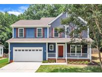 Charming two-story home with a blue exterior, red door, white trim, and an attached two car garage at 605 Catlin Rd, Cary, NC 27519