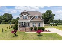 Charming two-story home featuring manicured landscaping and a welcoming front porch at 85 Twelve Oaks Dr, Willow Springs, NC 27592