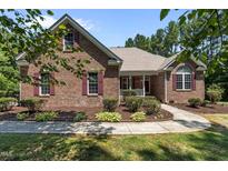 Charming brick home featuring manicured landscaping, red shutters, and a covered front porch at 9 Piney Grove Rd, Bahama, NC 27503