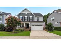 Beautiful two-story home with gray siding, stone accents, a covered porch, and a well-manicured front yard and 2-car garage at 908 Woodland Grove Way, Wake Forest, NC 27587