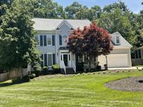 Charming two-story home with a well-manicured lawn and mature trees providing shade at 104 Belle Isle Ct, Cary, NC 27513