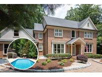 Beautiful brick home featuring a swimming pool, landscaped yard, and classic architectural details at 105 Woodsage Way, Cary, NC 27518