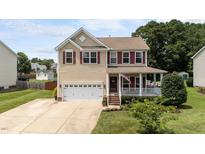 Charming two-story home with a front porch, a well-manicured lawn and a two car garage at 1713 Mclaurin Ln, Fuquay Varina, NC 27526
