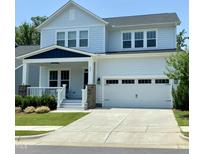 Charming two-story home with a covered front porch, white siding, and a two-car garage on a sunny day at 223 Chauncey Cir, Chapel Hill, NC 27516