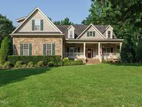 Charming two-story home with a stone facade, inviting front porch, and well-manicured lawn at 334 Dell Meadows Pl, Four Oaks, NC 27524