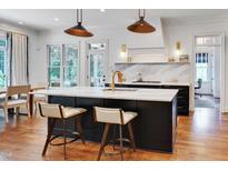 Bright kitchen with a large black island, marble countertops and backsplash, plus stainless steel appliances at 401 Westbury Dr, Chapel Hill, NC 27516