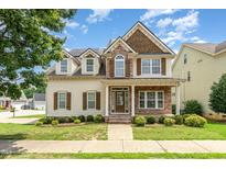 Inviting two-story home featuring stone accents, dormer windows, and a well-manicured front lawn at 410 Stranraer Ct, Fuquay Varina, NC 27526