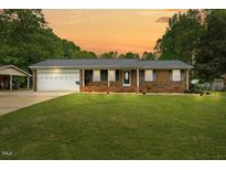 Charming brick home featuring a metal roof and well-manicured lawn at 410 W Tenth St, Siler City, NC 27344
