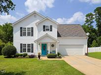Charming two-story home with a well-manicured lawn, two-car garage and inviting turquoise front door at 412 Onondaga Ct, Holly Springs, NC 27540