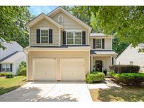 Charming two-story home boasts a two-car garage and classic curb appeal with lush landscaping and a welcoming entrance at 4524 Drewbridge Way, Raleigh, NC 27604