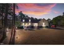 Charming yellow two-story home with dormers, a brick foundation, and a cozy front porch at 506 Tirzah Dr, Lillington, NC 27546