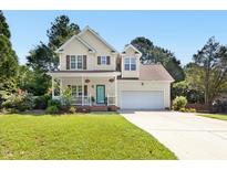 Charming two-story home boasts a welcoming porch, a well-manicured lawn, and an attached two car garage at 9416 Buggy Run Cir, Wake Forest, NC 27587
