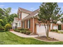 Charming brick home featuring a two-car garage, manicured lawn, and well-maintained landscaping at 11571 Auldbury Way, Raleigh, NC 27617