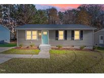 Charming single-story home with gray siding, black shutters, and a neatly landscaped front yard at dusk at 1203 Freeman Dr, Sanford, NC 27330