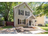 Charming two-story home featuring black shutters, a covered porch, and a meticulously landscaped yard at 1611 Poole Rd, Raleigh, NC 27610