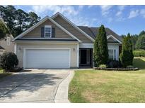 Charming home showcasing a tan exterior, attached garage, manicured lawn and mature trees at 421 Braxman Ln, Holly Springs, NC 27540