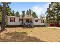 Charming single-story home featuring red shutters, a covered front porch, and mature trees at 51 Brafford Estates Dr, Cameron, NC 28326