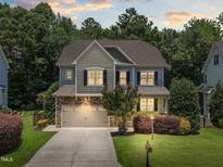Beautiful two-story home with a stone and siding exterior, attached garage, and professionally landscaped yard at 529 Lake Gaston Dr, Fuquay Varina, NC 27526