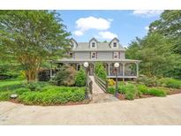 Charming two-story home features a covered porch, landscaped yard, and a picturesque bridge entrance at 53 Lake Wendell Rd, Wendell, NC 27591