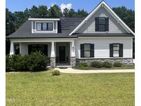 Charming home showcasing gray siding, black shutters, manicured lawn, and inviting front porch with stone accents at 820 Christian Light Rd, Fuquay Varina, NC 27526