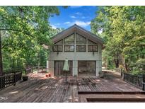 Modern home exterior featuring a spacious wooden deck and large windows, surrounded by lush trees at 8510 Dunlee Falls Rd, Raleigh, NC 27613