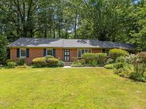 Charming brick home with a well-manicured lawn, mature trees, and lush landscaping at 111 Lattimore Ln, Durham, NC 27713