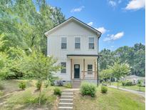 Charming two-story white home featuring a welcoming front porch and landscaped front yard at 1213 Grant St, Durham, NC 27701