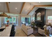 Bright living room boasts vaulted ceilings, wooden beams, sleek fireplace, and access to a screened-in porch at 16 Calming Pl Pl, Fuquay Varina, NC 27526