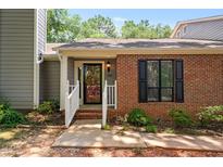 Charming brick home featuring a covered front entrance with white railing and updated black front door at 232 Clancy Cir, Cary, NC 27511