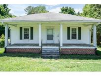 Charming single-story home featuring a covered front porch, white siding, and neatly trimmed dark green shutters at 310 Spring St, Durham, NC 27703