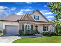 Charming two-story home boasts stone accents, a covered porch, an attached garage, and manicured landscaping at 3106 Royal Deeside Ct, Zebulon, NC 27597